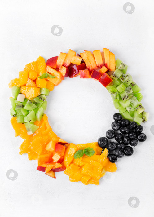 Скачать Ассорти из нарезанных фруктов и ягод, обрамляющее круглое пространство для копирования на белом фоне. Нектарин, апельсин, манго, киви и черника. фотосток Ozero