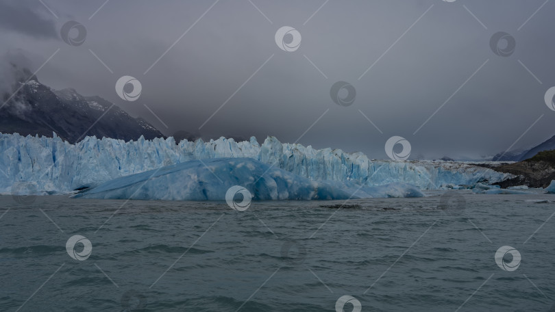 Скачать Стена голубого льда с острыми вершинами и трещинами возвышается в бирюзовом озере. фотосток Ozero