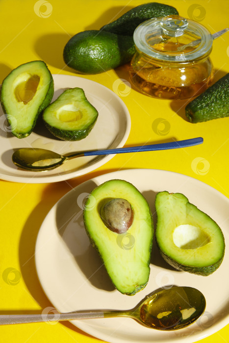 Скачать Ломтики авокадо на тарелках со свежим авокадо на желтом фоне, твердый светлый фотосток Ozero