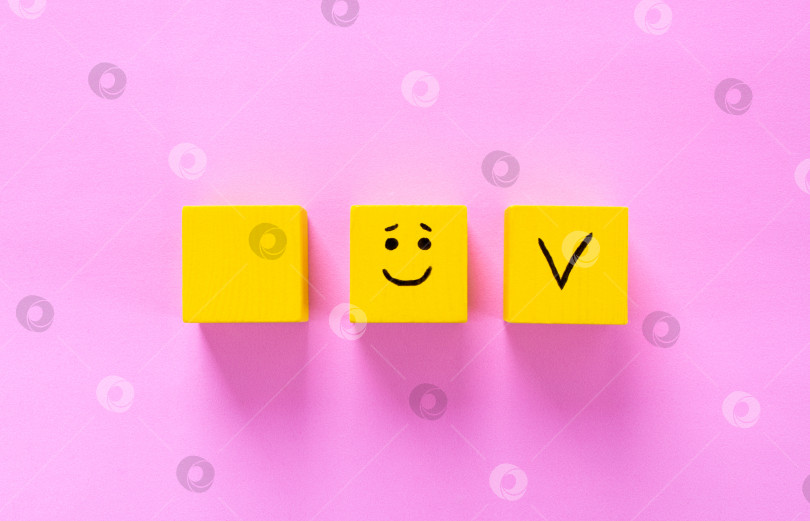 Скачать Концепция удовлетворенности клиентов. Желтые кубики с улыбающимся лицом и галочкой на розовом. Пространство для копирования. фотосток Ozero