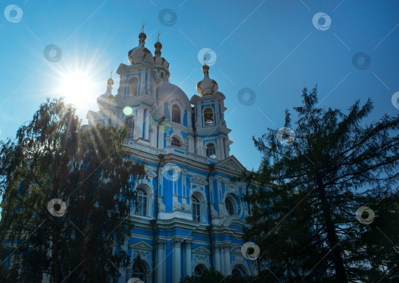 Скачать Санкт-Петербург, Россия - 28 августа 2021 года: Смольный собор, освещенный солнечными лучами на фоне голубого неба. фотосток Ozero