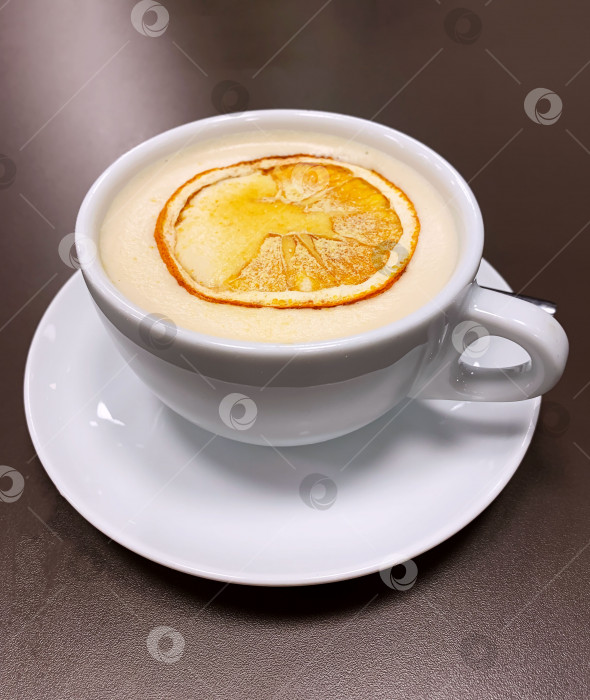 Скачать На столе стоит белая чашка кофе с долькой апельсина фотосток Ozero