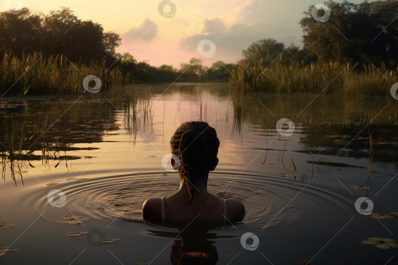 Скачать Вид сзади на одинокую афроамериканскую девушку, стоящую в воде в диком озере на открытом воздухе фотосток Ozero