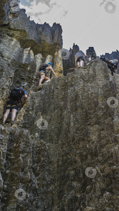 Скачать Туристы взбираются на скалу с защитным снаряжением. фотосток Ozero