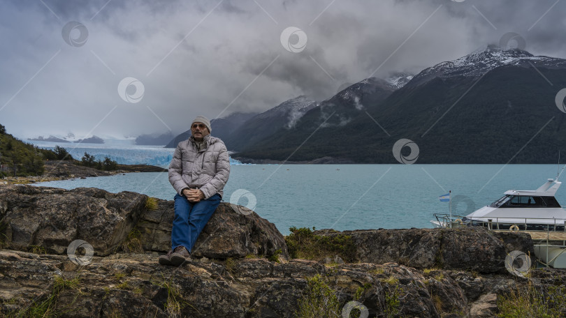 Скачать Мужчина сидит на камне на берегу бирюзового ледникового озера и смотрит вдаль. фотосток Ozero