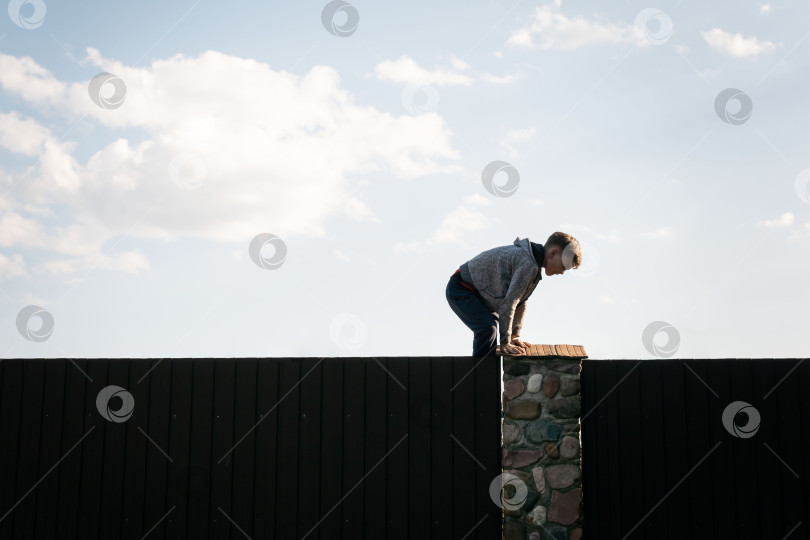 Скачать Маленький мальчик перелезает через забор фотосток Ozero
