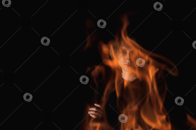 Скачать Взгляд взрослого парня сквозь огонь в полной темноте фотосток Ozero