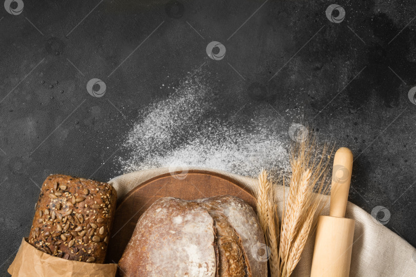 Скачать Разнообразные виды домашнего ржаного и пшеничного хлеба на столе из черного камня. Вид сверху с местом для вашего текста. фотосток Ozero