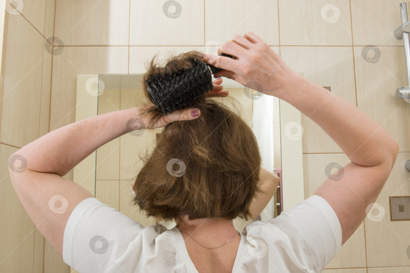 Скачать Женщина расчесывает волосы перед зеркалом фотосток Ozero