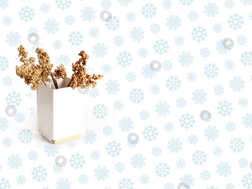 Скачать Белая современная ваза с золотой ветвью, выделенной на белом фоне синими снежинками фотосток Ozero