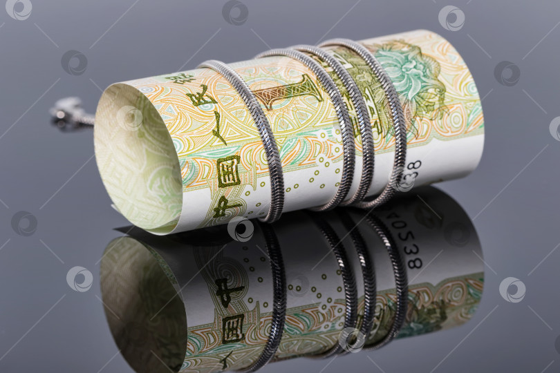 Скачать банкнота в один юань обернута вокруг серебряной цепочки фотосток Ozero