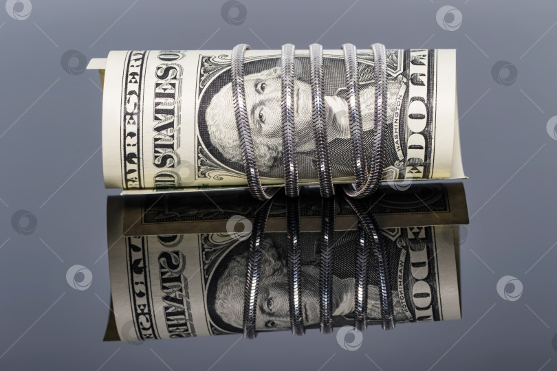 Скачать однодолларовая банкнота обернута вокруг серебряной цепочки со змеиной сеткой фотосток Ozero