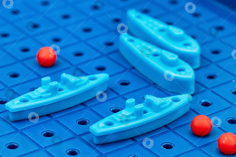 Скачать Игрушечные военные корабли и подводная лодка размещены на синем игровом поле фотосток Ozero