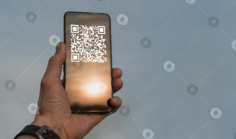 Скачать Мужчина держит в руках смартфон с QR-кодом фотосток Ozero