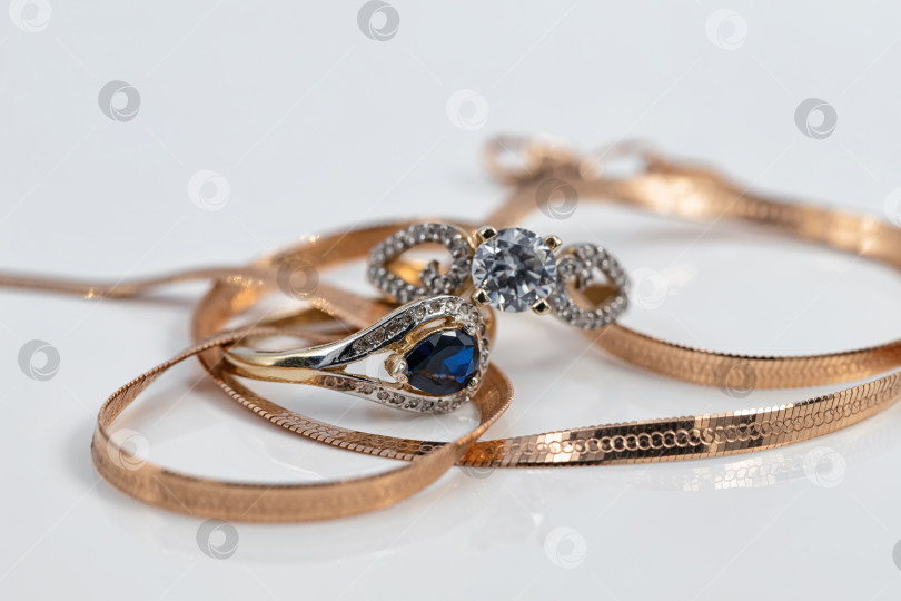 Скачать Два женских золотых кольца разной формы с разными драгоценными камнями и элегантная золотая цепочка фотосток Ozero