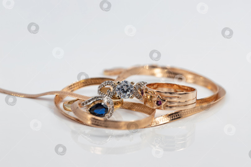 Скачать Три женских золотых кольца разной формы с разными драгоценными камнями и элегантная золотая цепочка фотосток Ozero
