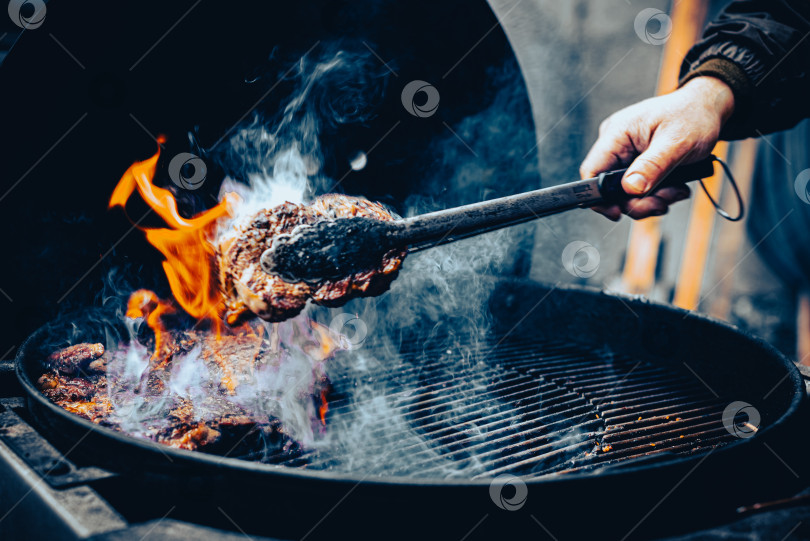Скачать Пламя мерцает, когда мясо шипит на гриле фотосток Ozero