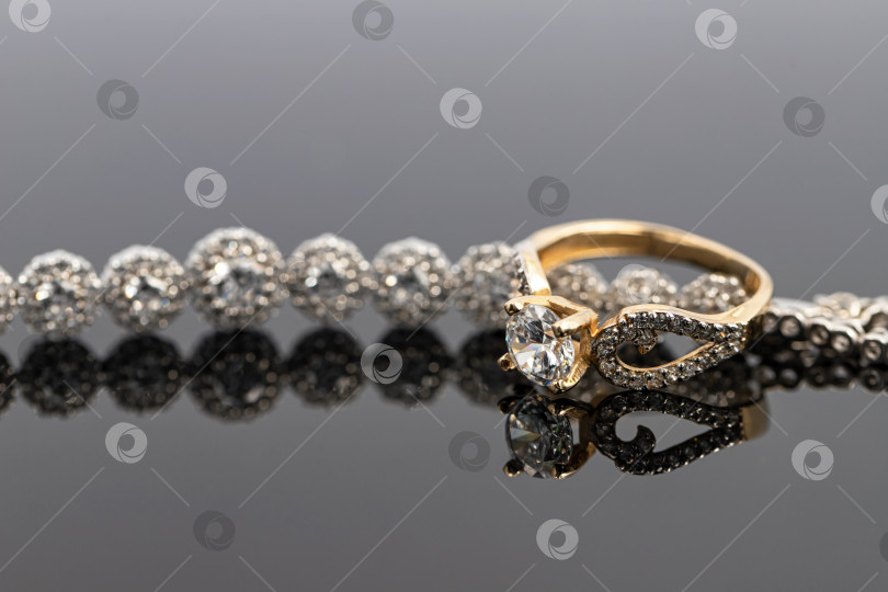 Скачать Элегантное женское золотое кольцо с бриллиантом надето на браслет с драгоценными камнями фотосток Ozero