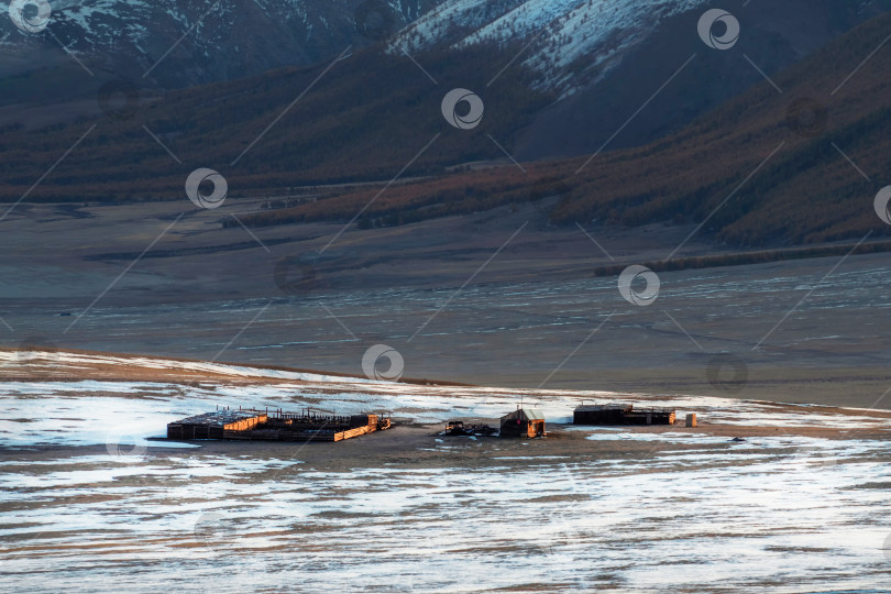 Скачать Небольшой домик, конура и загон для скота у подножия заснеженной горы на Алтае, на берегу замерзшей реки. фотосток Ozero