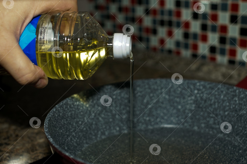 Скачать Растительное масло льется из бутылки на дно сковороды. фотосток Ozero