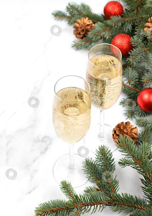 Скачать Два бокала шампанского на элегантном праздничном фоне с еловыми ветками и украшениями, концепция Сочельника. Рождественский и новогодний макет для дизайна и демонстрации продукции, фотосток Ozero