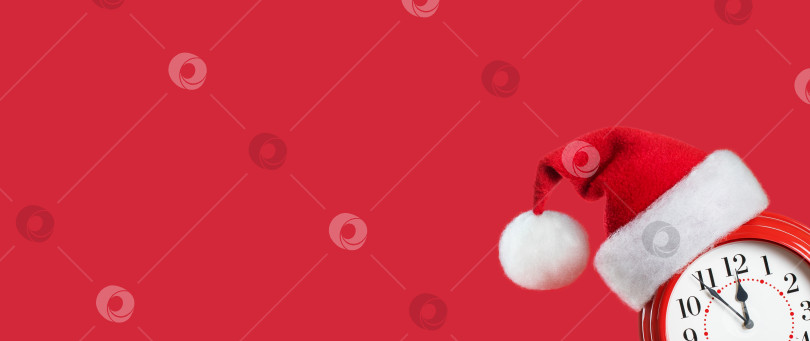 Скачать Красный будильник в шапке Деда Мороза выглядывает из нижнего угла кадра фотосток Ozero