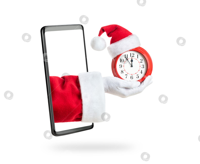 Скачать Рука Деда Мороза держит красный будильник в красной шапочке и выходит из экрана смартфона фотосток Ozero