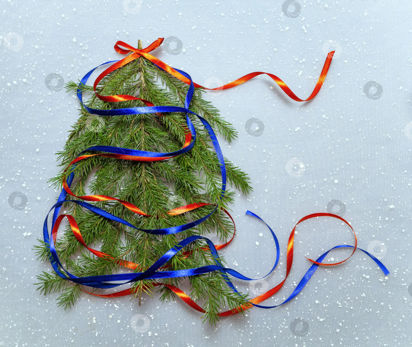 Скачать Красочный рождественский фон с рождественской елкой. Красные и синие ленты украшают ель. На верхушке дерева - красный бант фотосток Ozero