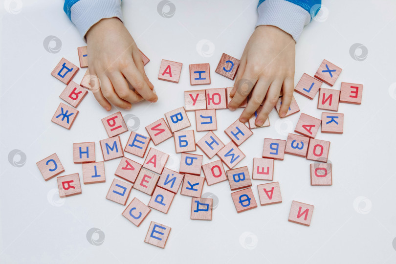Скачать Руки ребенка крупным планом держат деревянные кубики с буквами и алфавитом на белом фоне фотосток Ozero