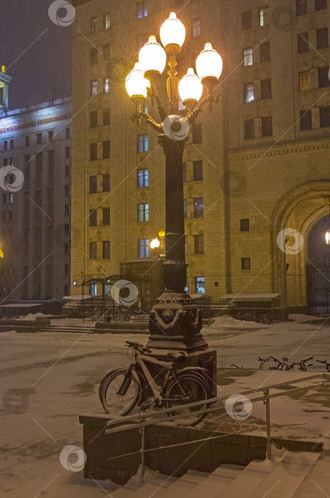 Скачать Заснеженные велосипеды, прислоненные к фонарному столбу. фотосток Ozero