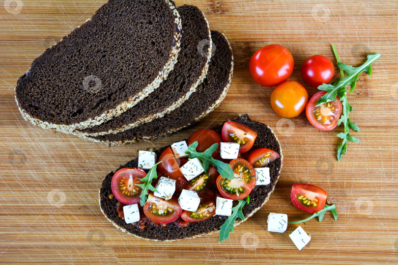Скачать Сочный бутерброд с помидорами, сыром и зеленью на черном хлебе с хлопьями фотосток Ozero