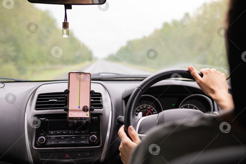 Скачать Вид сзади на юного путешественника, пользующегося навигатором на мобильном телефоне за рулем современного автомобиля. фотосток Ozero