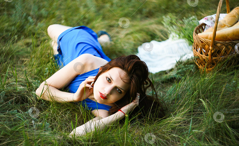 Скачать Красивая девушка лежит на траве с корзинкой и хлебом фотосток Ozero