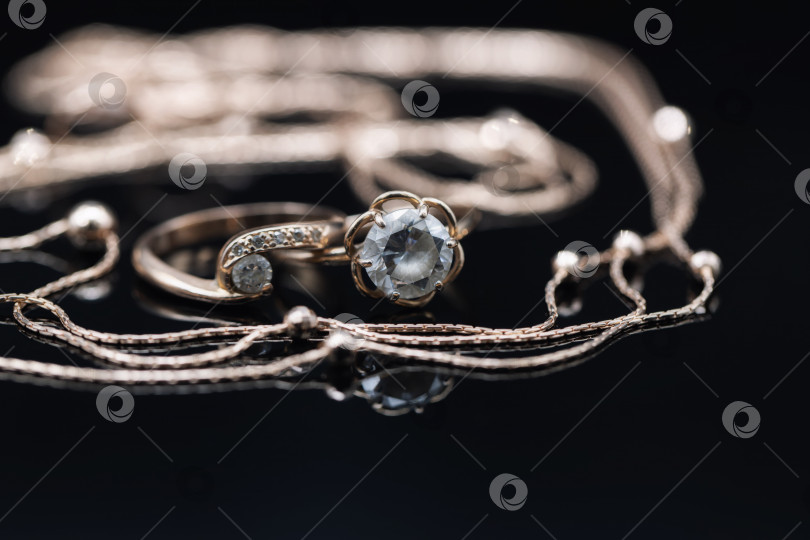 Скачать Золотые кольца с драгоценными камнями разного размера и элегантная золотая цепочка фотосток Ozero