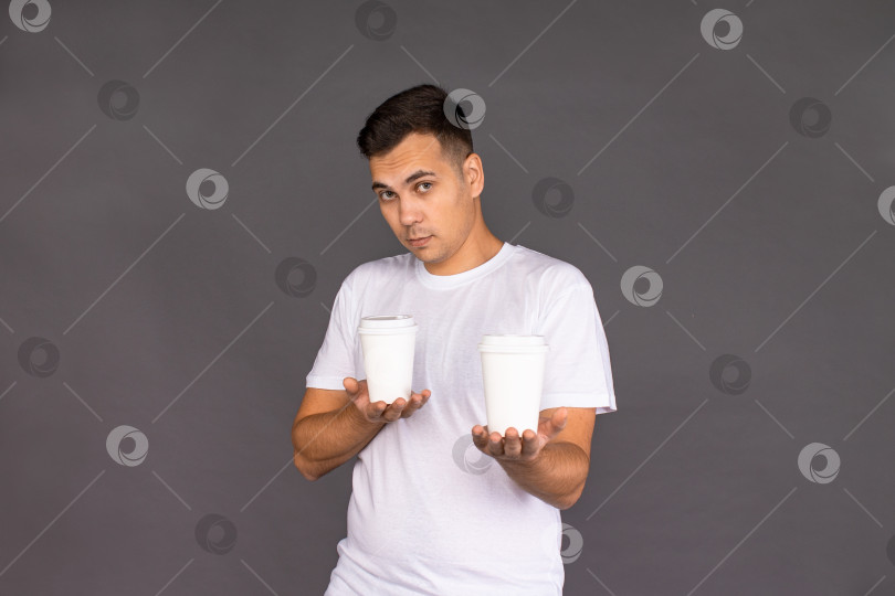 Скачать Парень в белой футболке пытается выбрать между двумя сортами кофе. фотосток Ozero