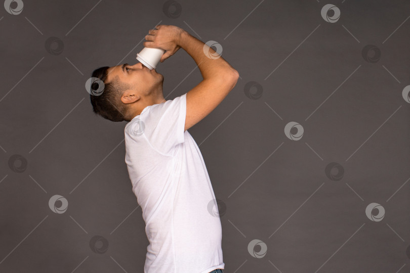 Скачать Парень в белой футболке жадно пьет кофе по утрам. фотосток Ozero