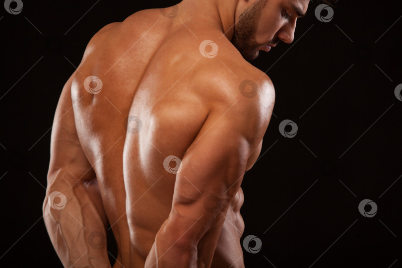Скачать Сильный спортивный мужчина - Фитнес-модель, демонстрирующая свою идеальную спину, изолированную на черном фоне с copyspace фотосток Ozero
