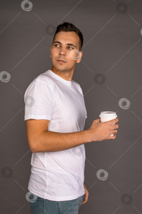 Скачать Парень в белой футболке держит в руках стаканы с кофе. фотосток Ozero