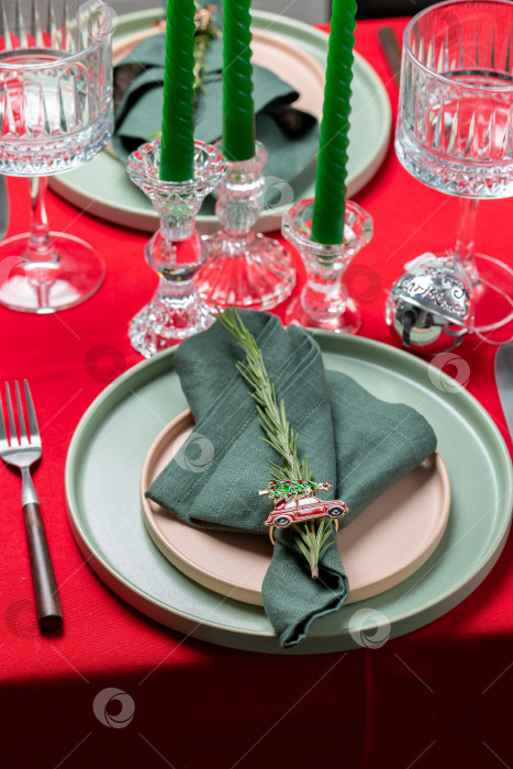 Скачать Рождественский сервиз для ужина, красная льняная скатерть, две тарелки, зеленая салфетка с веточкой розмарина фотосток Ozero