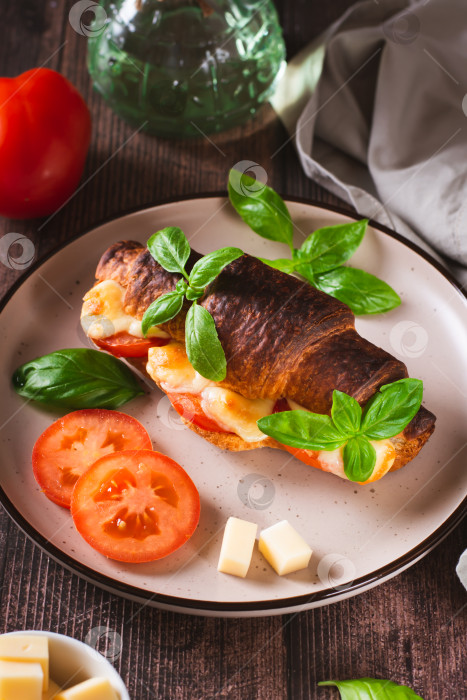 Скачать Запеченный круассан капрезе с помидорами, сыром и базиликом на тарелке, вид сверху фотосток Ozero