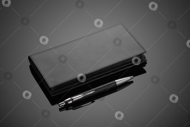 Скачать Крупным планом модный кожаный мужской бумажник и ручка на черном фоне фотосток Ozero