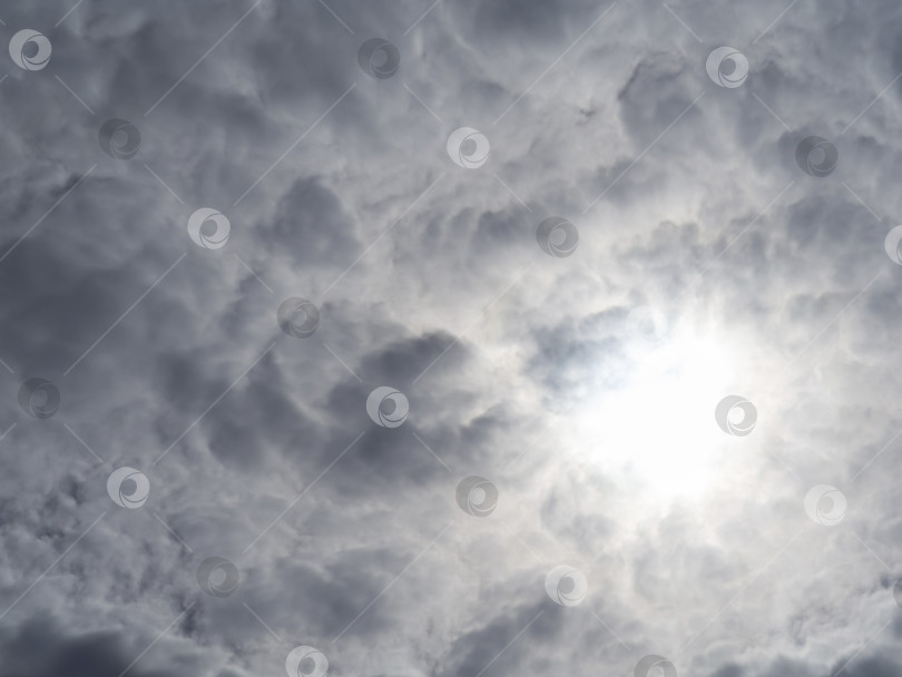 Скачать Сплошные кучевые облака и пробивающееся сквозь них бледное солнце, текстурированный фон облаков фотосток Ozero