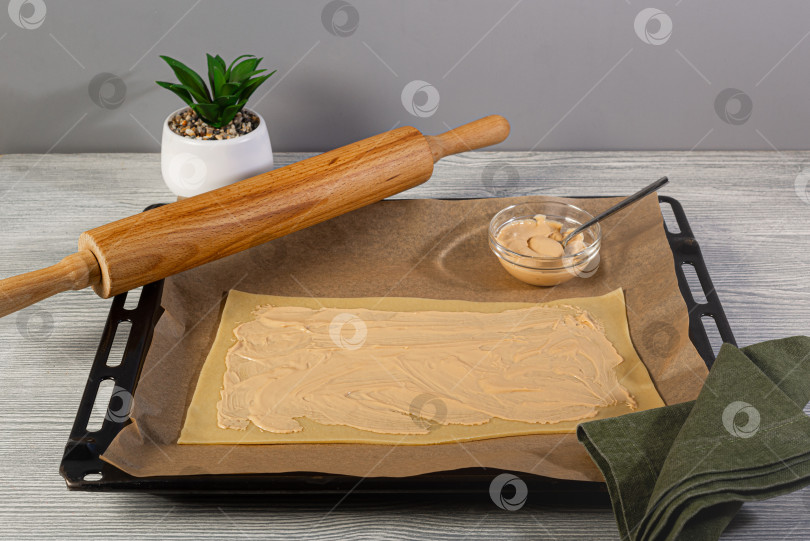 Скачать Кусочек сырого дрожжевого теста выложите на противень, смазанный сладкой сливочной начинкой, на пергаментную бумагу для выпечки фотосток Ozero