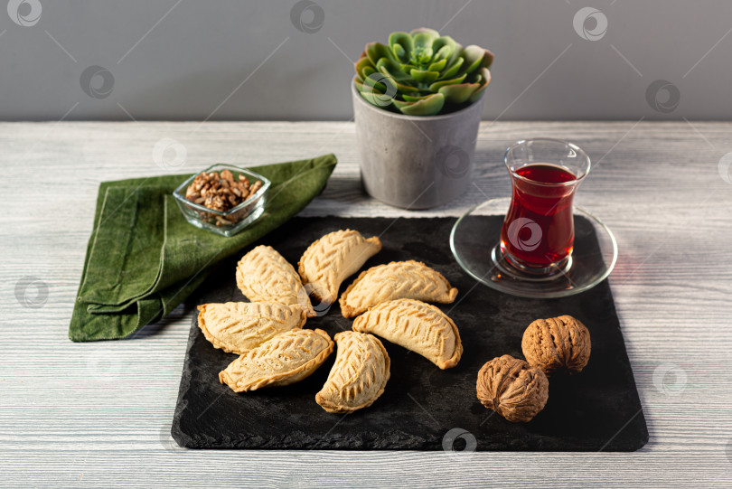 Скачать Классическое азербайджанское печенье Шекербура с начинкой из грецких орехов в сочетании с красным чаем в бокале армуду. фотосток Ozero