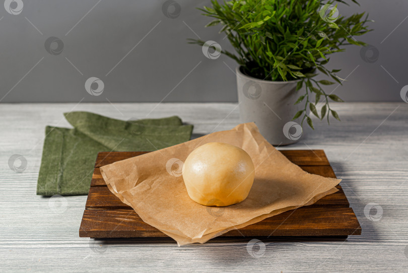 Скачать Тесто выложите на пергаментную бумагу поверх деревянной поверхности, накройте зеленой салфеткой на сером фоне фотосток Ozero