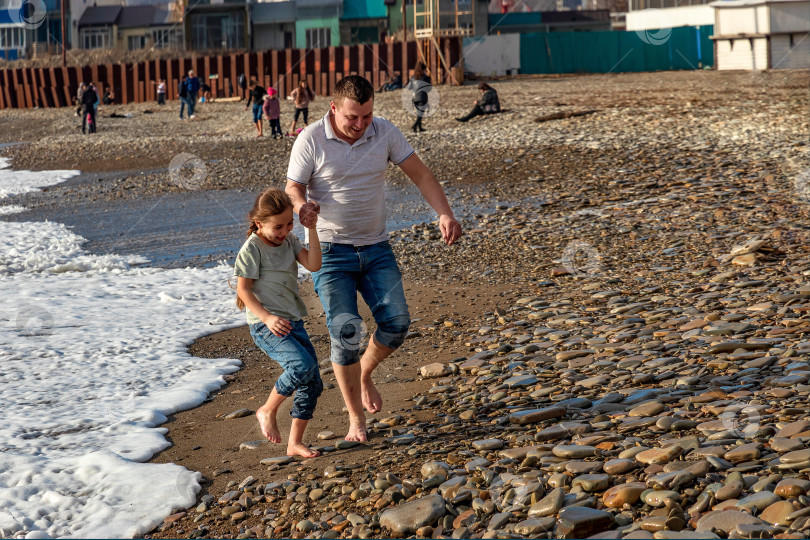 Скачать Отец и дочь на пляже, убегают от набегающих волн. фотосток Ozero