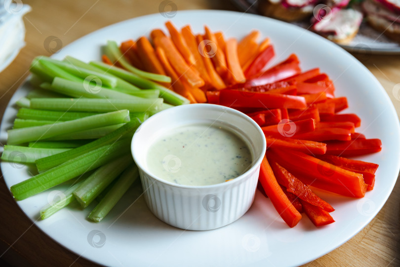 Скачать нарезанные овощные палочки на белой тарелке с соусом для макания крупным планом фотосток Ozero