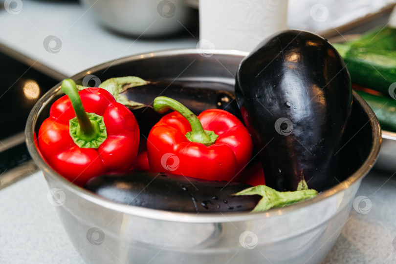 Скачать Баклажаны и болгарский перец выложите в миску на кухонном столе. Сырые овощи перед приготовлением. фотосток Ozero