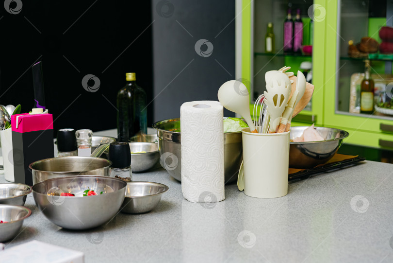 Скачать Кухонные инструменты и кулинарная утварь на столе. Набор мисок, бумажное полотенце и ингредиенты. фотосток Ozero