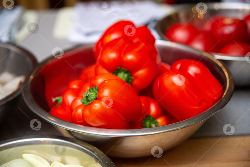 Скачать Свежий красный болгарский перец в металлической миске на кухонном столе. фотосток Ozero
